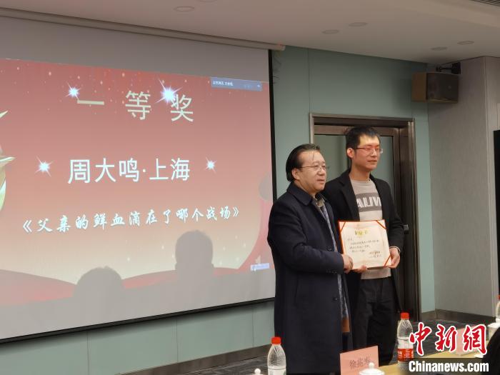 圖為作家、西北師范大學(xué)新聞與傳媒學(xué)院院長(zhǎng)徐兆壽頒發(fā)一等獎(jiǎng)證書(shū)，代領(lǐng)獎(jiǎng)?wù)呱吓_(tái)領(lǐng)獎(jiǎng)。　楊娜 攝