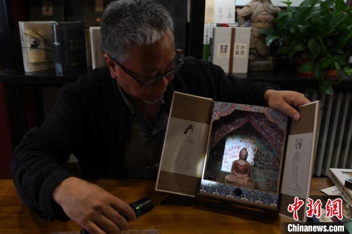 圖為讀者出版集團(tuán)讀者晉林工作室獨(dú)立出品人徐晉林，展示互動(dòng)性強(qiáng)的敦煌題材手工書。(資料圖) 楊艷敏 攝