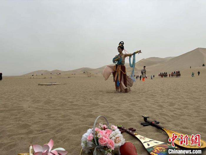 圖為2023年4月底，敦煌大漠“逐舞者”奧楠在鳴沙山月牙泉景區(qū)視頻直播敦煌舞?！●T志軍 攝