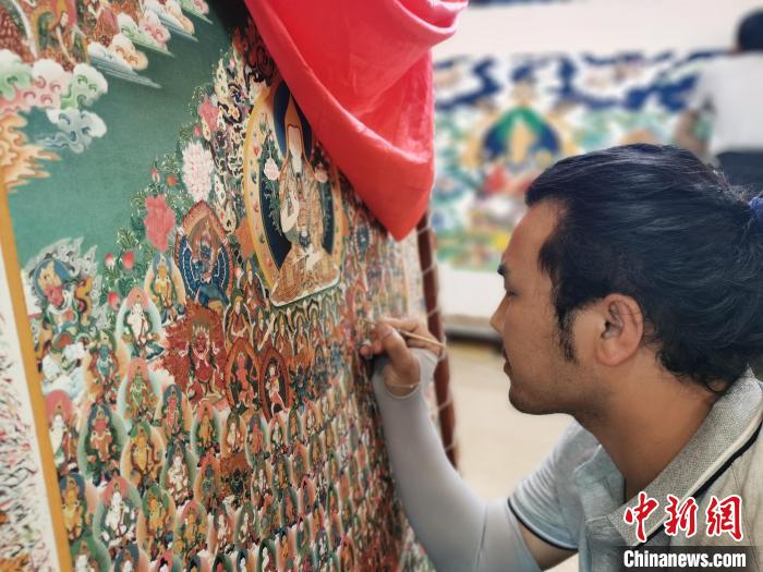 圖為更登才讓的徒弟繪畫唐卡?！?zhí)砀?攝