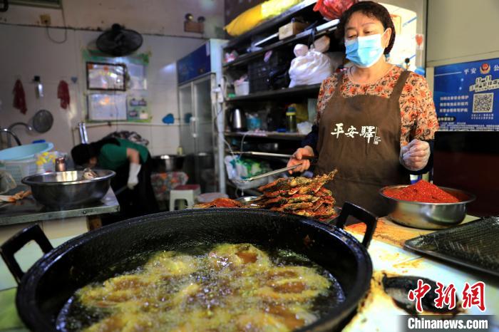 圖為平安驛·河湟民俗文化體驗(yàn)地內(nèi)的商戶炸干板魚?！⊙Φ?攝